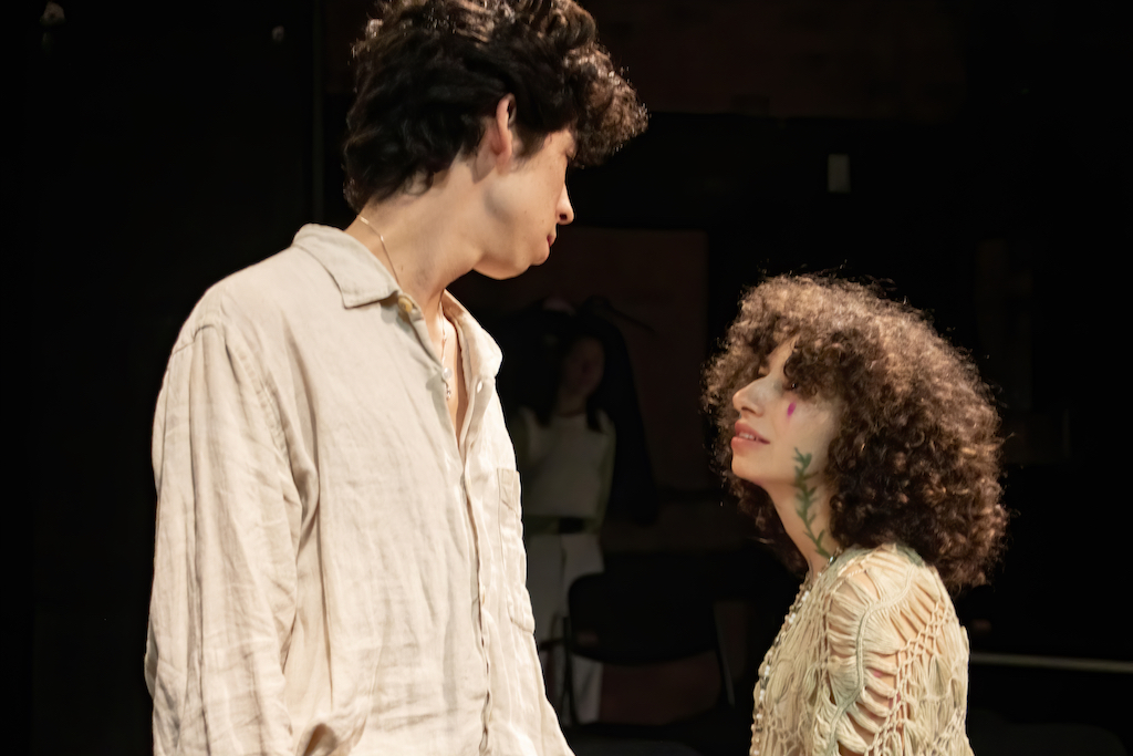 Close-up photo of two actors looking at one another in mid-performance.